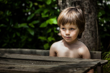 niño sentado en un pupitre de madera en verano en un jardín