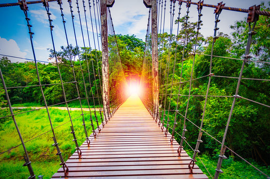 Suspension bridge or Bridge hanger with the light at the end of the walkway.