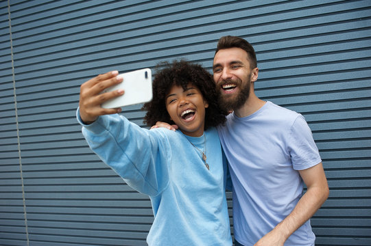 girl and hipster guy taking selfie on a street