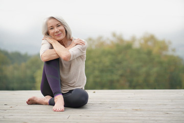   Beautiful elderly woman sitting outdoors in sportswear