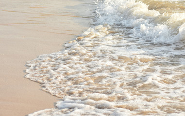 Fluffy bubbles of sea waves rushing on the beach of Lunta island, Krabi, Thailand.