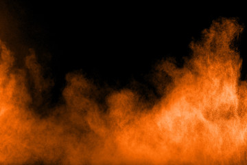 Abstract orange powder explosion on black  background. Freeze motion of orange  dust particles splash.