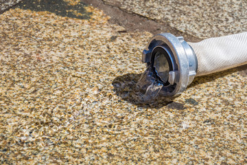 Water leaking from a fire hose to the ground