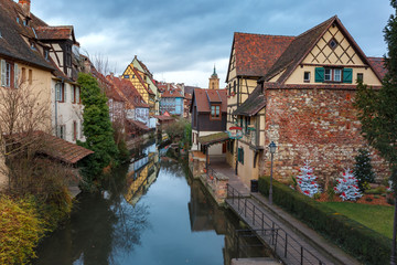 Fototapeta na wymiar Traditional Alsatian half-timbered houses, church and river Lauch in Petite Venise or little Venice, old town of Colmar, decorated at christmas time, Alsace, France