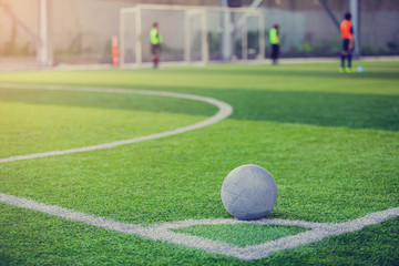 Ball on artificial turf at corner of football field with blurry player.