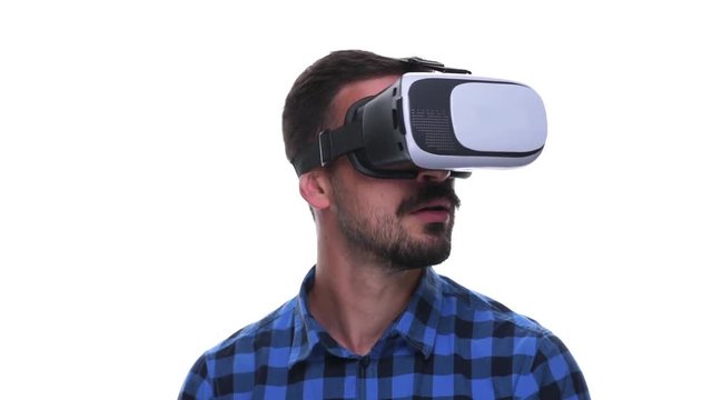 Impressed young millennial wearing virtual reality headset looking around speechless isolated on white background. 