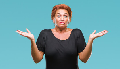 Atrractive senior caucasian redhead woman over isolated background clueless and confused expression...