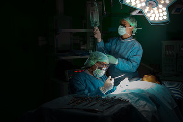 Several surgeons surrounding patient on operation table during their work.Medical team performing...
