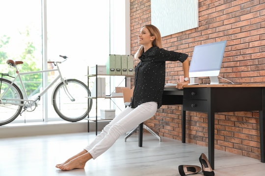 Young businesswoman stretching at workplace. Productivity boost