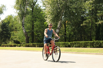 Fototapeta premium Attractive man riding bike outdoors on sunny day