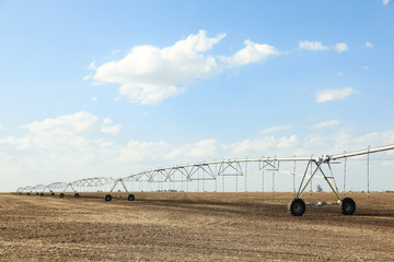 Field with irrigation system on sunny day