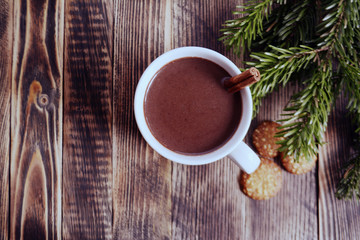 Obraz na płótnie Canvas Hot chocolate or cocoa with cinnamon stick in a cup and fir branches. Winter hot drink for cold weather. New year and Christmas concept Top view Copy space
