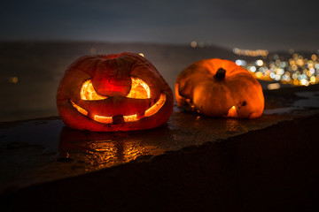 Horror Halloween concept. Close up view of scary dead Halloween pumpkin glowing at dark background.