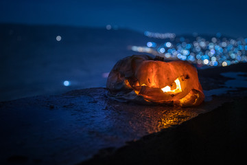 Horror Halloween concept. Close up view of scary dead Halloween pumpkin glowing at dark background.