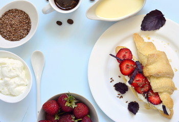 Croissant with cream cheese, strawberries and basil for breakfast, top view, copy space