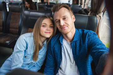 adult happy man taking selfie with beautiful girlfriend during trip on travel bus