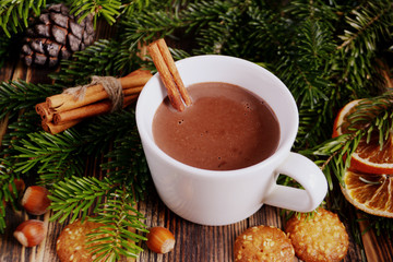 Obraz na płótnie Canvas Hot chocolate or cocoa with cinnamon stick in a cup and fir branches. Winter hot drink for cold weather. New year and Christmas concept