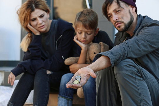 Poor homeless family begging on city street