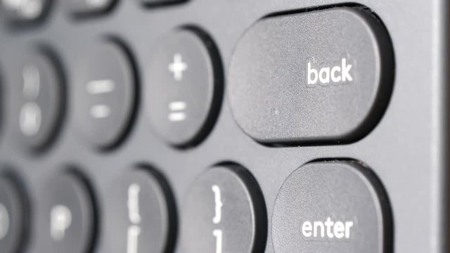 Closeup of finger pressing backspace button on the black computer keyboard. Technology