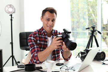Portrait of photo blogger with camera and laptop at home. Online broadcast