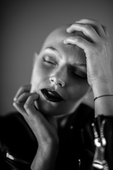 Fototapeta premium Emotive portrait of a beautiful bald woman while covering her face with her hands.
