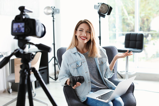 Female photo blogger recording video on camera indoors