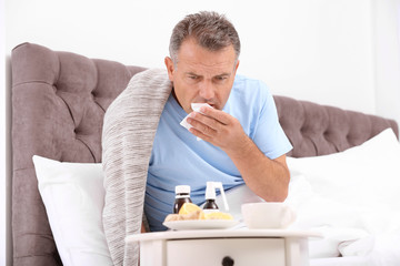 Man suffering from cough and cold in bed at home
