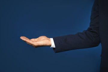 Obraz premium Businessman holding something on color background, closeup of hand