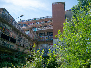 Exterior of an old abandoned building or factory, completely destroyed and vandalized, painted with colourful graffiti street art