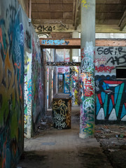 Hallway in an old abandoned building or factory, completely destroyed and vandalized, painted with colourful graffiti street art