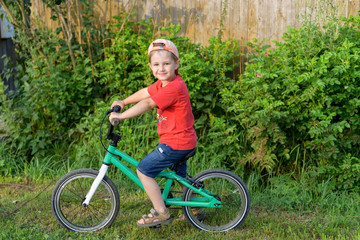 Fototapeta na wymiar Portrait of little boy with his bike in hands on country road, learn to cycling, outdoors