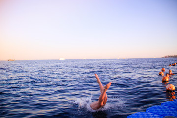 The girl in a blue bikini dives into the water. Leap in the red sea in Egypt. Red-haired woman Water splashes.