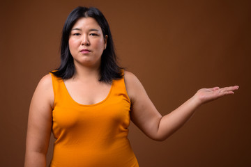 Beautiful overweight Asian woman showing copy space