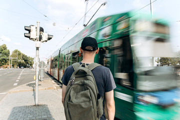 Young guy or male tourist on a street or a crossroads or near the road in Leipzig in Germany. Near the city tram in motion.