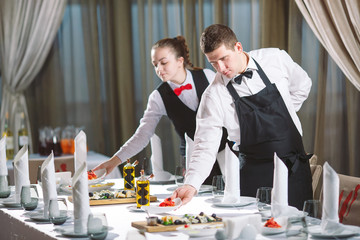 Waiters serving table in the restaurant preparing to receive guests.