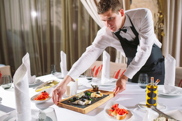 Fototapeta premium Waiter serving table in the restaurant preparing to receive guests.