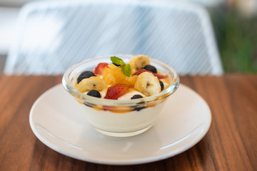 A bowl of yogurt and fruits on a wooden table