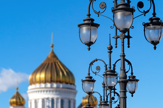 Cast iron street lamps on the Patriarch's Bridge against the blue sky and golden domes