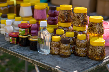different honey in plastic jars stands on a wooden street counter
