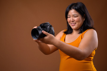 Fototapeta premium Beautiful overweight Asian woman photographer using camera