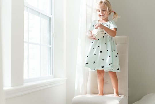 Girl standing a chair holding a decorative pumpkin