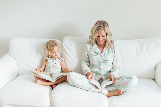 Mother and daughter reading a book while sitting on a sofa