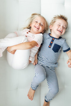 Brother and sister lying down next to each other smiling