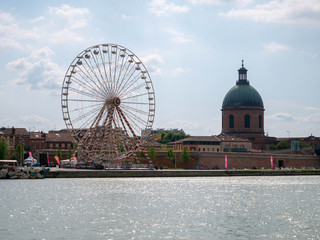Cityscape with ferris wheel and a cathedral seen from across the river Garonne in Toulouse, France