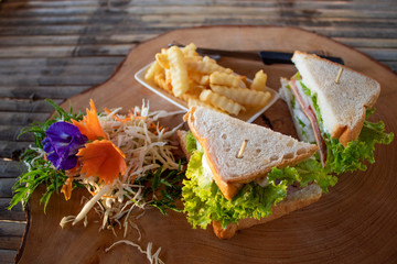 Delicious sandwich with French fries served on wooden board