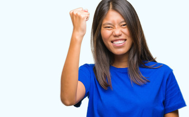 Young asian woman over isolated background angry and mad raising fist frustrated and furious while shouting with anger. Rage and aggressive concept.