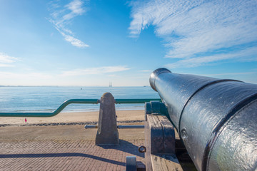 Ancient cannon protecting the coast of the dutch city of Vlissingen below a blue sky 