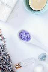 Fototapeta na wymiar Flowers of lavender, decorative bottle, lemon, white soap, sea salt in a spoon and seashells on tha white background.