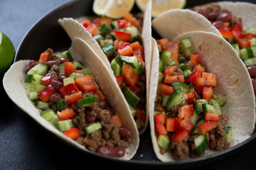 Close-up of tacos with ground beef meat, red beans and fresh vegetables, selective focus, studio shot