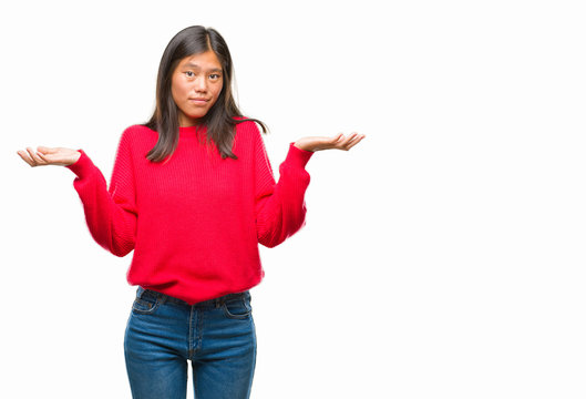 Young asian woman wearing winter sweater over isolated background clueless and confused expression with arms and hands raised. Doubt concept.